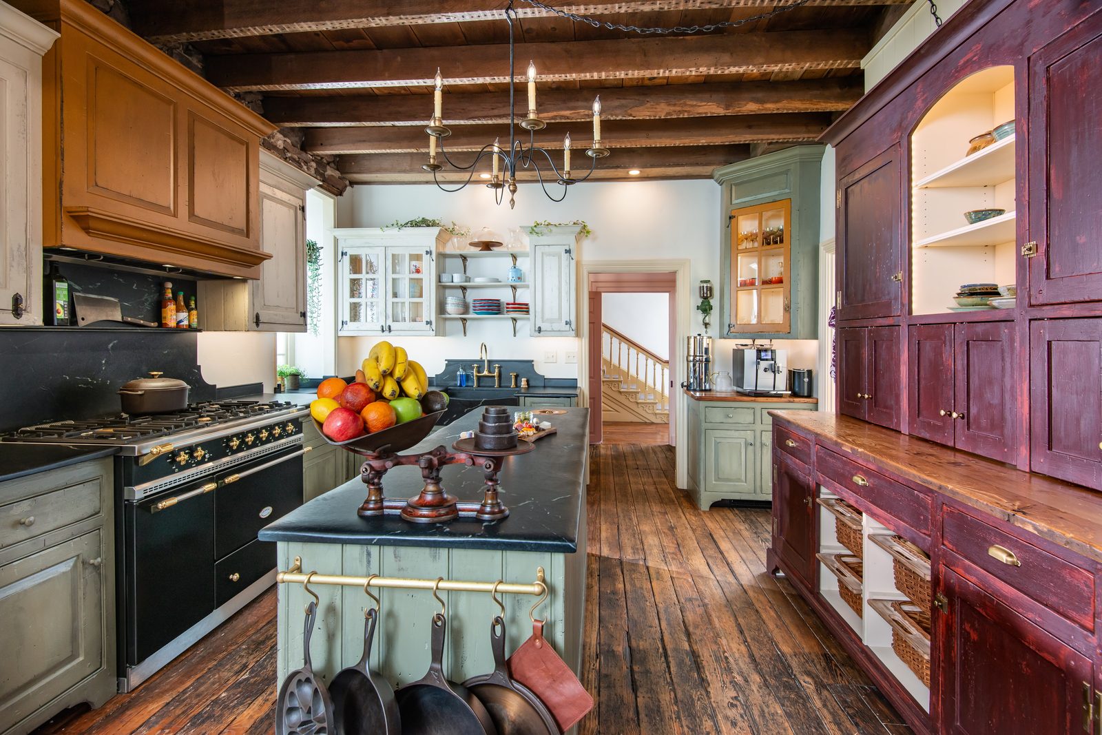 Kitchen with vaulted ceiling, original farmhouse joists exposed overhead, and an iron chandelier