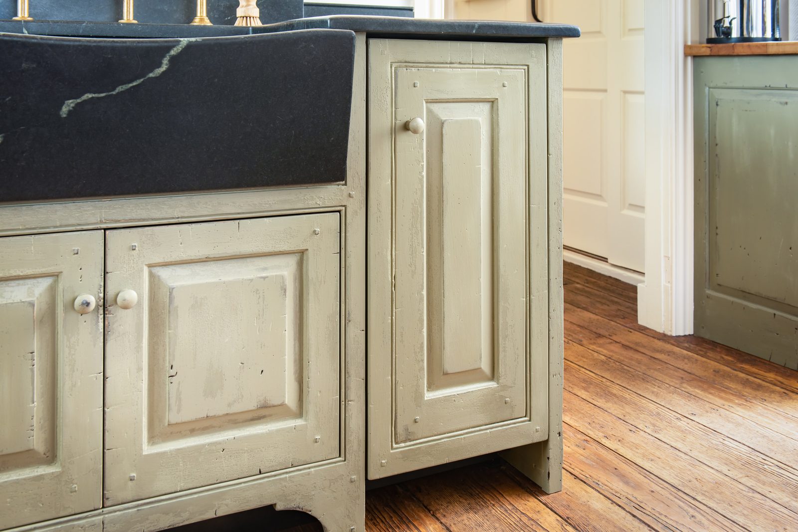 Soapstone farmhouse sink in sage-green base cabinet