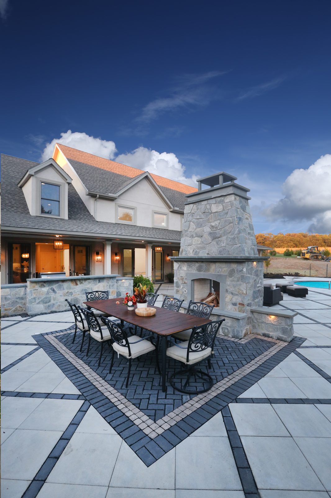 Rear elevation with stone fireplace, dining patio, and pool beyond