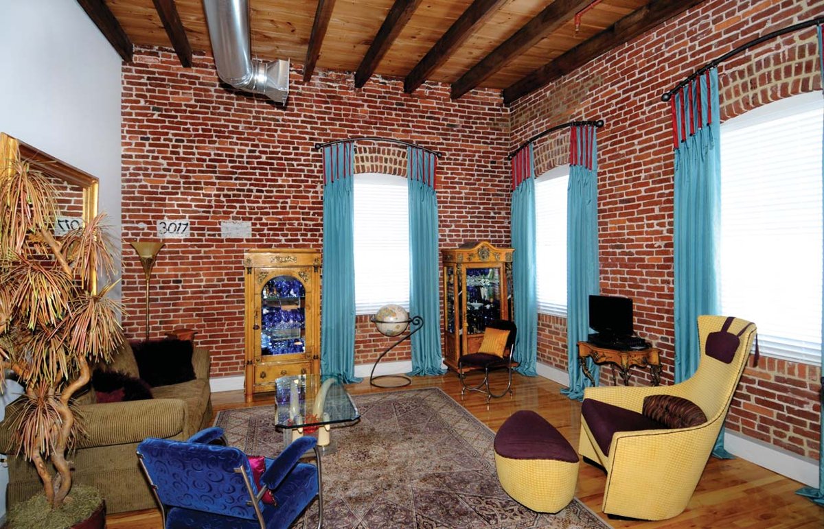 Loft living room with original brick walls, exposed beams, and arched brick window openings