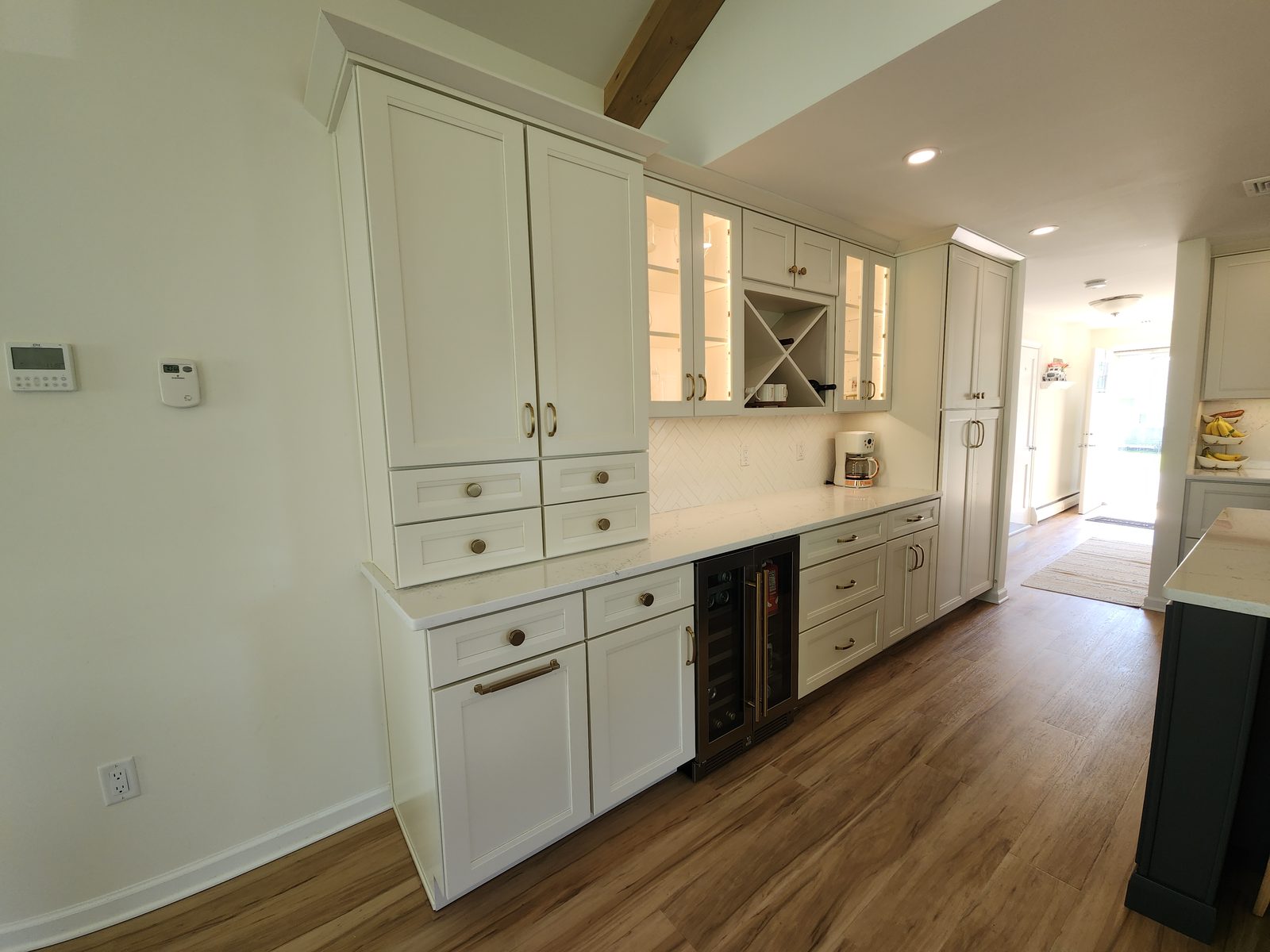 Custom white cabinetry with wine fridge and herringbone backsplash